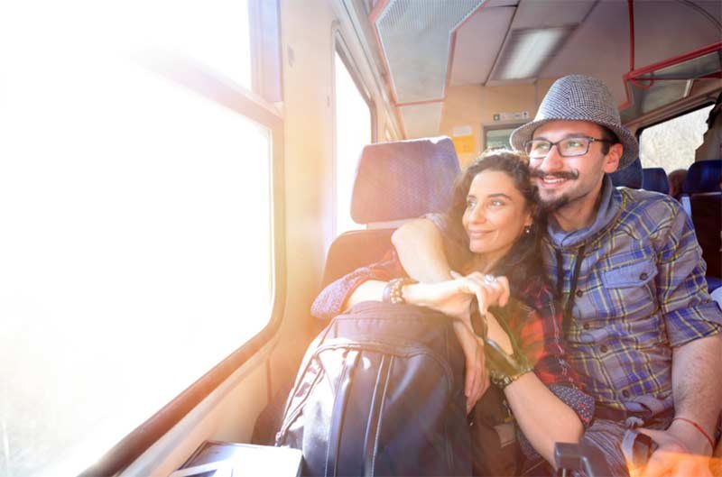 A couple sitting inside a train looking out of a window