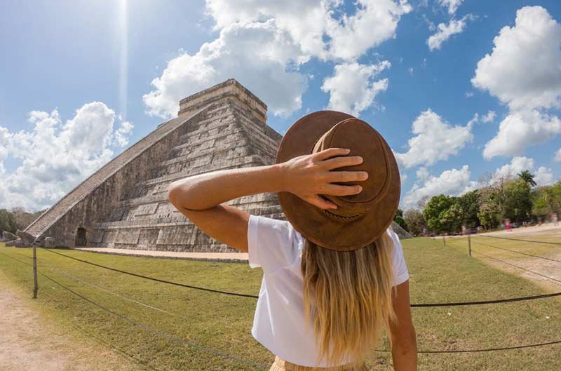 A girl in hat looking up at a pyramid